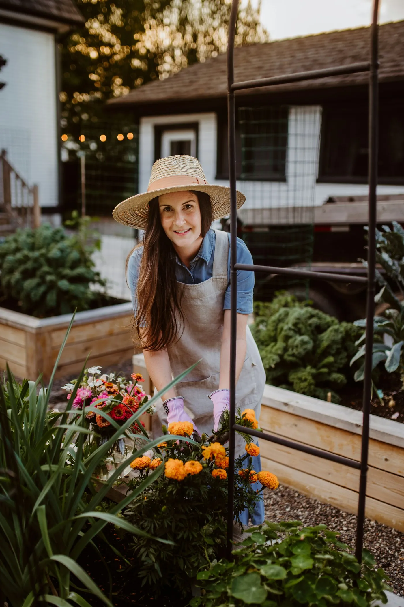 A gardener in a sun hat and gloves tending plants