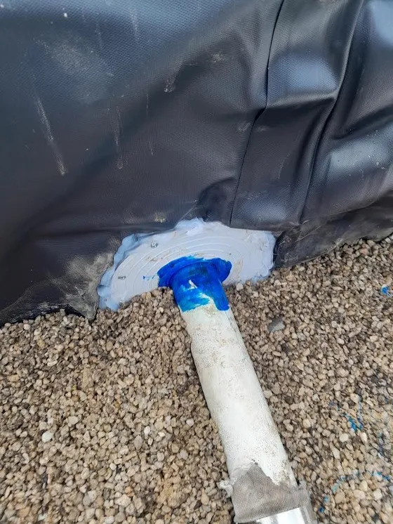 A 50 mm flange siliconed and screwed through the liner, with a pipe cemented through it